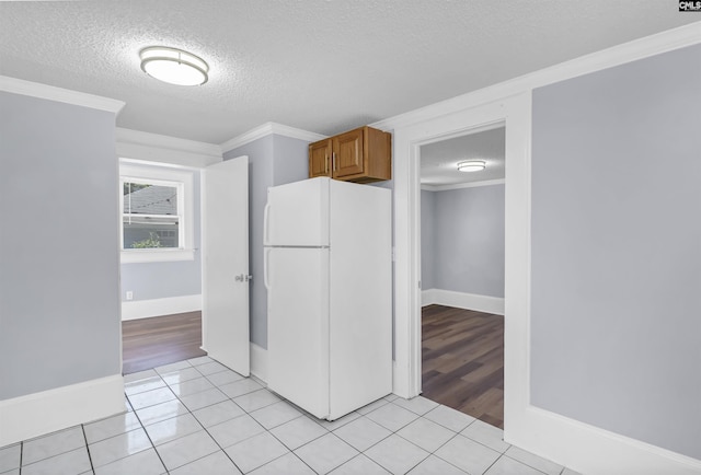 2217 Blossom St, Columbia, SC 29205 - kitchen featuring freestanding refrigerator, a textured ceiling, ornamental molding, brown cabinetry, and light tile patterned floors