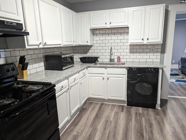 2217 Blossom St, Columbia, SC 29205 - kitchen with black appliances, a sink, under cabinet range hood, dark wood-type flooring, and white cabinetry