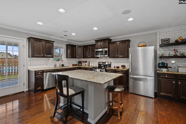 2 Casey Dr, Elgin, SC 29045 - kitchen with appliances with stainless steel finishes, tasteful backsplash, dark brown cabinetry, ornamental molding, and a breakfast bar