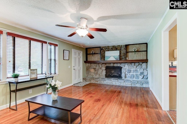 1178 Dothan Rd, Columbia, SC 29210 - living area featuring ornamental molding, a textured ceiling, wood finished floors, ceiling fan, and a stone fireplace