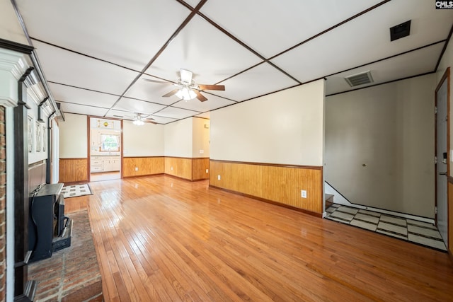 108 Commonwealth Ct, Lexington, SC 29073 - unfurnished living room with wainscoting, hardwood / wood-style floors, a ceiling fan, a wood stove, and wood walls
