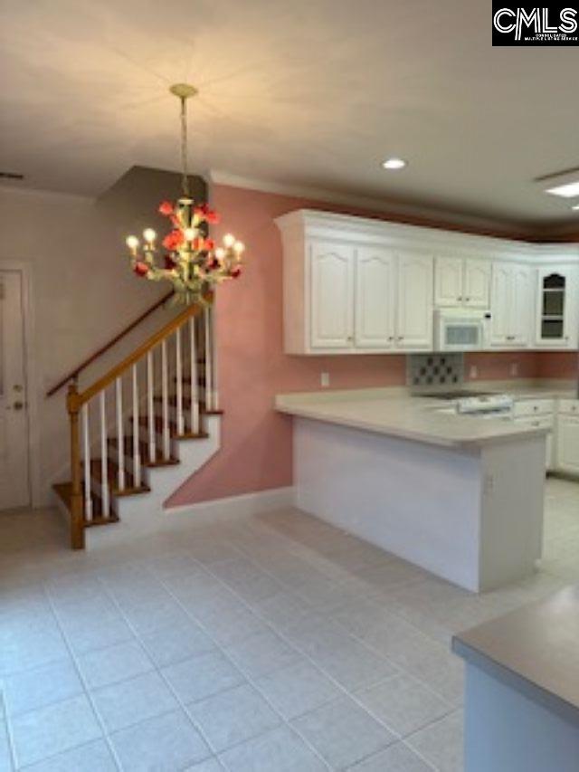 117 York Commons, Lexington, SC 29072 - kitchen featuring white microwave, white cabinetry, light countertops, a chandelier, and a peninsula