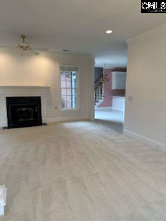117 York Commons, Lexington, SC 29072 - unfurnished living room with ceiling fan, ornamental molding, stairs, a fireplace with flush hearth, and carpet