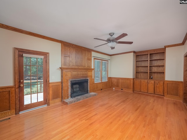 117 Falmouth Rise Rd, Columbia, SC 29229 - unfurnished living room featuring crown molding, wainscoting, light wood-style floors, a ceiling fan, and a brick fireplace