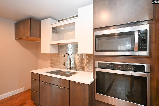 2110 Bouknight St, Newberry, SC 29108 - kitchen featuring stainless steel appliances, a sink, light countertops, wood finished floors, and backsplash
