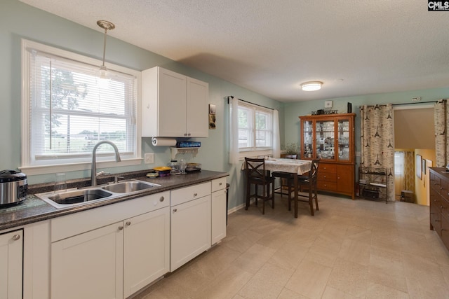 1921 Cunningham Rd, Columbia, SC 29210 - kitchen featuring a sink, dark countertops, a textured ceiling, white cabinets, and hanging light fixtures