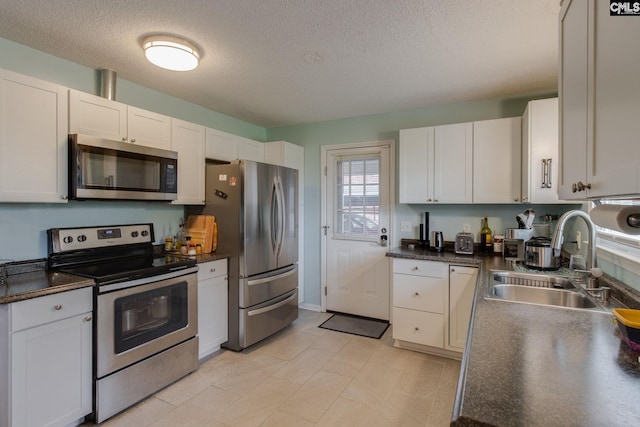 1921 Cunningham Rd, Columbia, SC 29210 - kitchen with appliances with stainless steel finishes, a sink, a textured ceiling, dark countertops, and white cabinetry