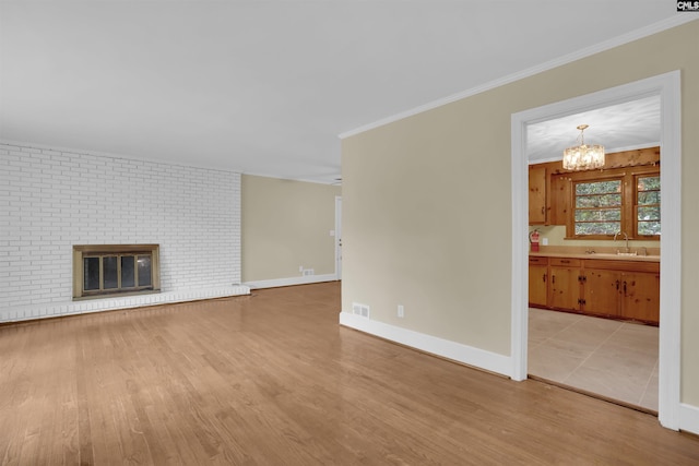 1669 Upland Dr, Columbia, SC 29204 - unfurnished living room featuring light wood-type flooring, a sink, a chandelier, crown molding, and baseboards