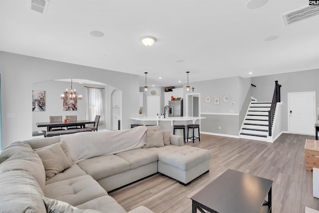 1051 Ashcroft Cir, Columbia, SC 29229 - living area with arched walkways, stairs, light wood-style floors, a chandelier, and baseboards