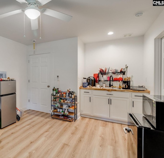 3308 Keenan Dr, Columbia, SC 29201 - kitchen with freestanding refrigerator, black microwave, light wood finished floors, white cabinets, and ceiling fan