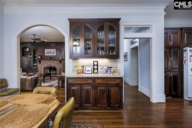 7021 Cleaton Rd, Columbia, SC 29206 - bar area featuring a ceiling fan, dark wood-style flooring, a fireplace, crown molding, and arched walkways
