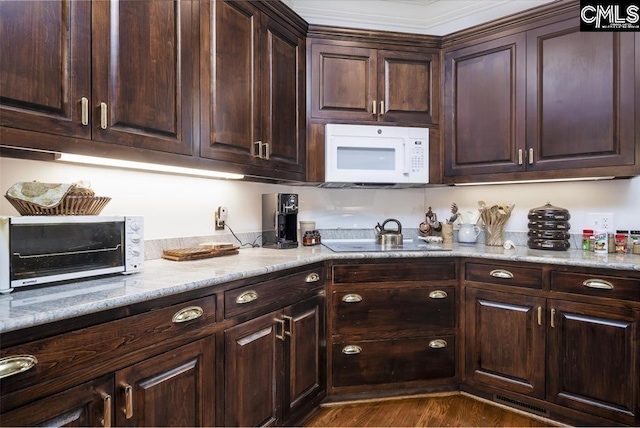 7021 Cleaton Rd, Columbia, SC 29206 - kitchen featuring white microwave, dark brown cabinets, black electric cooktop, dark wood-style floors, and light stone counters