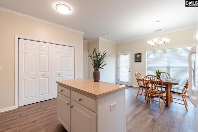 209 Windsor Trace Dr, Columbia, SC 29209 - kitchen with wood finished floors, a chandelier, ornamental molding, a kitchen island, and white cabinetry