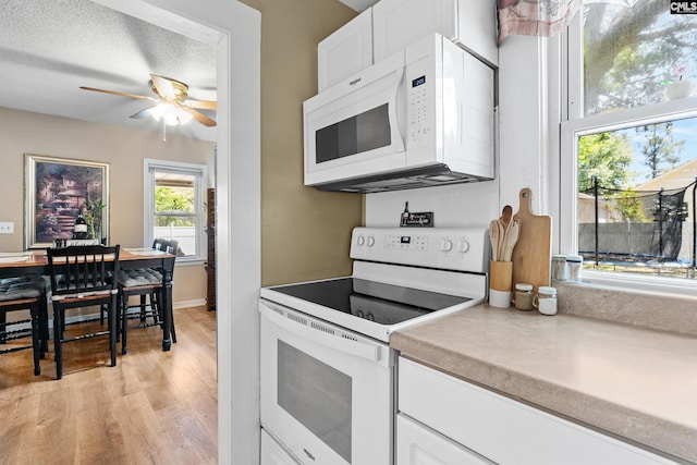319 Graham St, West Columbia, SC 29169 - kitchen featuring white appliances, ceiling fan, white cabinetry, light wood-style flooring, and light countertops