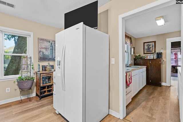 319 Graham St, West Columbia, SC 29169 - kitchen with white refrigerator with ice dispenser, light wood-style flooring, a sink, and baseboards
