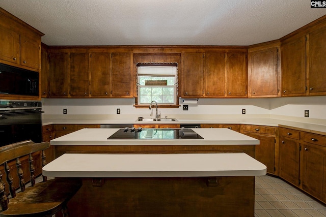 589 White Pines Cir, Camden, SC 29020 - kitchen with black appliances, a sink, light countertops, a kitchen island, and a textured ceiling