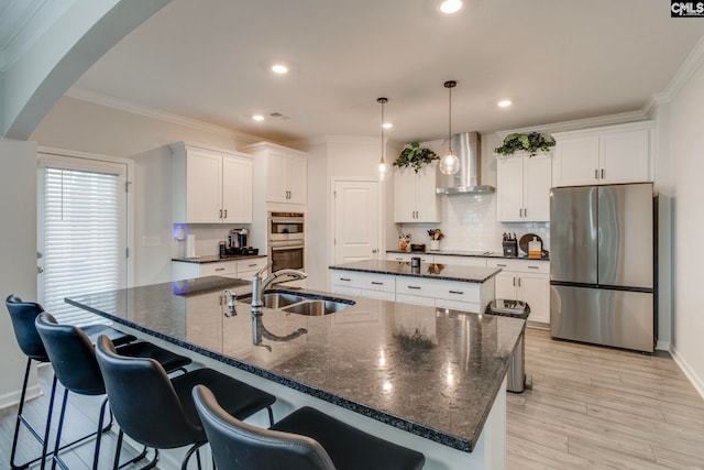 137 Brockway Dr, Columbia, SC 29229 - kitchen featuring stainless steel appliances, wall chimney exhaust hood, a kitchen island with sink, a sink, and arched walkways
