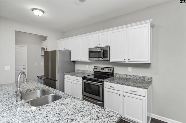 246 Harvest Glen Ln, West Columbia, SC 29169 - kitchen with stainless steel appliances, a sink, white cabinets, and light stone countertops