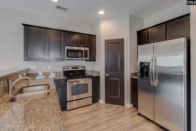 301 Chestnut Oak Ct, West Columbia, SC 29169 - kitchen featuring appliances with stainless steel finishes, a sink, light stone countertops, dark brown cabinets, and light wood-type flooring