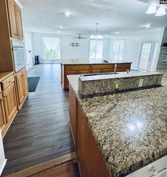 916 Sessions Rd, Elgin, SC 29045 - kitchen with white oven, a kitchen island, brown cabinetry, a textured ceiling, and dark wood-style floors