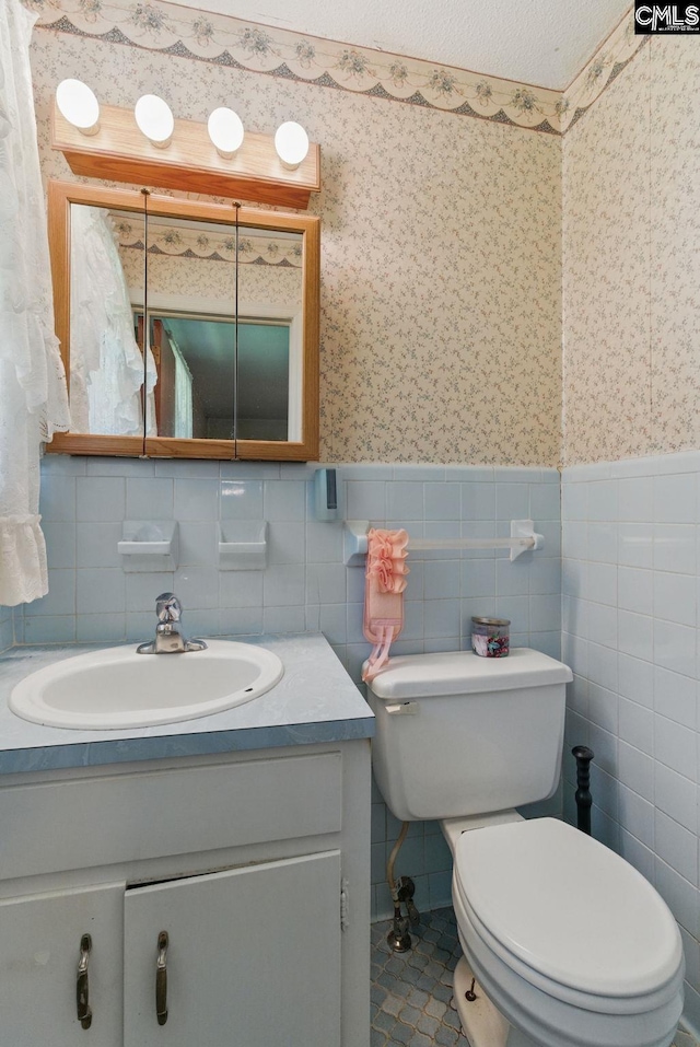 2015 Valley View Rd, West Columbia, SC 29172 - half bath featuring wallpapered walls, vanity, toilet, a wainscoted wall, and tile walls