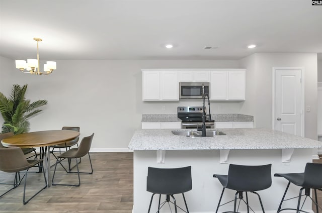 341 Liliana Dr, Columbia, SC 29223 - kitchen with a sink, stainless steel appliances, a chandelier, white cabinetry, and wood finished floors