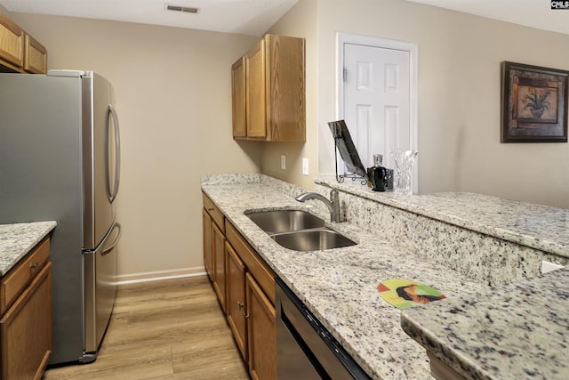 1306 Waverly Place Dr, Columbia, SC 29223 - kitchen featuring appliances with stainless steel finishes, a sink, light wood-type flooring, light stone countertops, and brown cabinetry