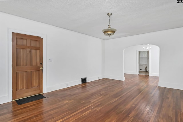 709 Sunset Dr, Columbia, SC 29203 - spare room featuring arched walkways, wood finished floors, a textured ceiling, a chandelier, and baseboards