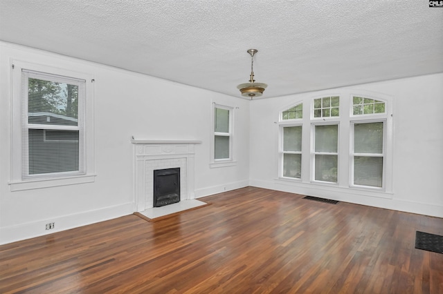 709 Sunset Dr, Columbia, SC 29203 - unfurnished living room with wood finished floors, healthy amount of natural light, a fireplace with flush hearth, a textured ceiling, and baseboards