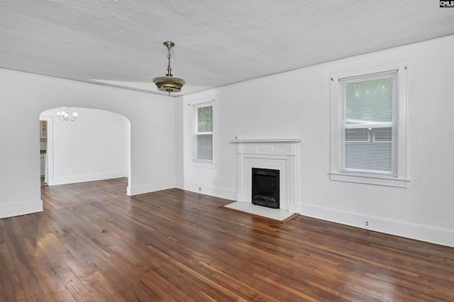 709 Sunset Dr, Columbia, SC 29203 - unfurnished living room featuring arched walkways, wood finished floors, a textured ceiling, a fireplace, and baseboards