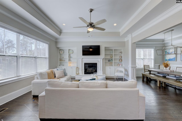 2 Beaver Lake Ct, Elgin, SC 29045 - living room featuring a tray ceiling, built in features, ceiling fan, a glass covered fireplace, and crown molding