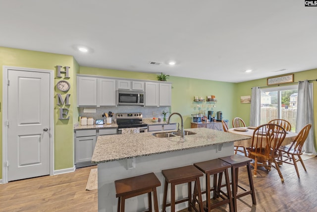 133 Plum Orchard Dr, West Columbia, SC 29170 - kitchen featuring appliances with stainless steel finishes, a sink, a breakfast bar, light wood-type flooring, and a kitchen island with sink
