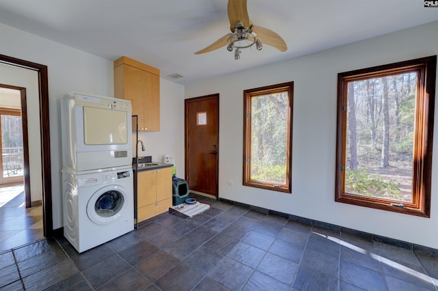 208 Gibbs Rd, Elgin, SC 29045 - laundry area featuring estacked washer and dryer, cabinet space, a ceiling fan, baseboards, and stone tile flooring