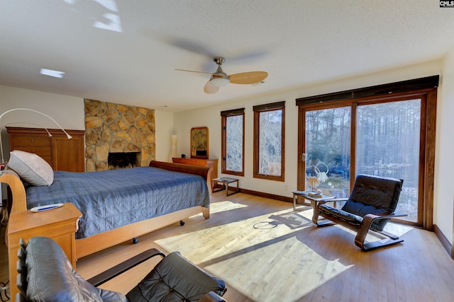 208 Gibbs Rd, Elgin, SC 29045 - bedroom featuring access to outside, light wood finished floors, baseboards, a ceiling fan, and a stone fireplace