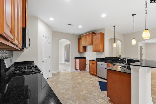309 Tanners Mill Ct, Chapin, SC 29036 - kitchen featuring appliances with stainless steel finishes, arched walkways, a sink, a peninsula, and brown cabinets