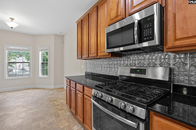 309 Tanners Mill Ct, Chapin, SC 29036 - kitchen with stainless steel appliances, brown cabinetry, decorative backsplash, dark stone counters, and baseboards