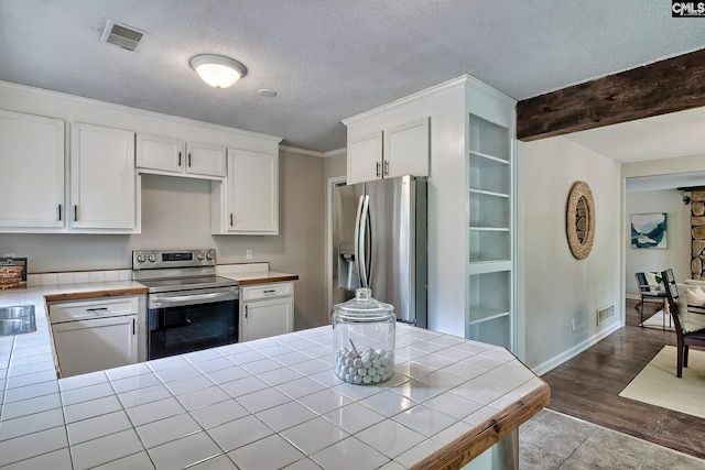 1820 Elm Abode Ter, Columbia, SC 29210 - kitchen with stainless steel appliances, tile counters, white cabinets, wood finished floors, and a textured ceiling