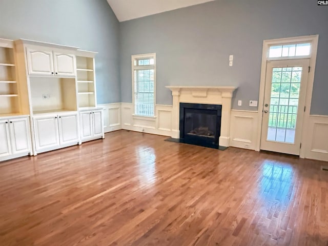 601 Cartgate Cir, Blythewood, SC 29016 - unfurnished living room with high vaulted ceiling, wood finished floors, a wainscoted wall, a fireplace with flush hearth, and a decorative wall