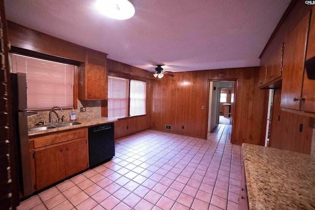 109 Mcrae St, Columbia, SC 29203 - kitchen featuring black dishwasher, a sink, plenty of natural light, light countertops, and wooden walls