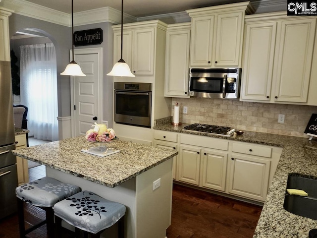 522 Meadow Grass Ln, Lexington, SC 29072 - kitchen featuring appliances with stainless steel finishes, arched walkways, ornamental molding, light stone countertops, and a kitchen bar