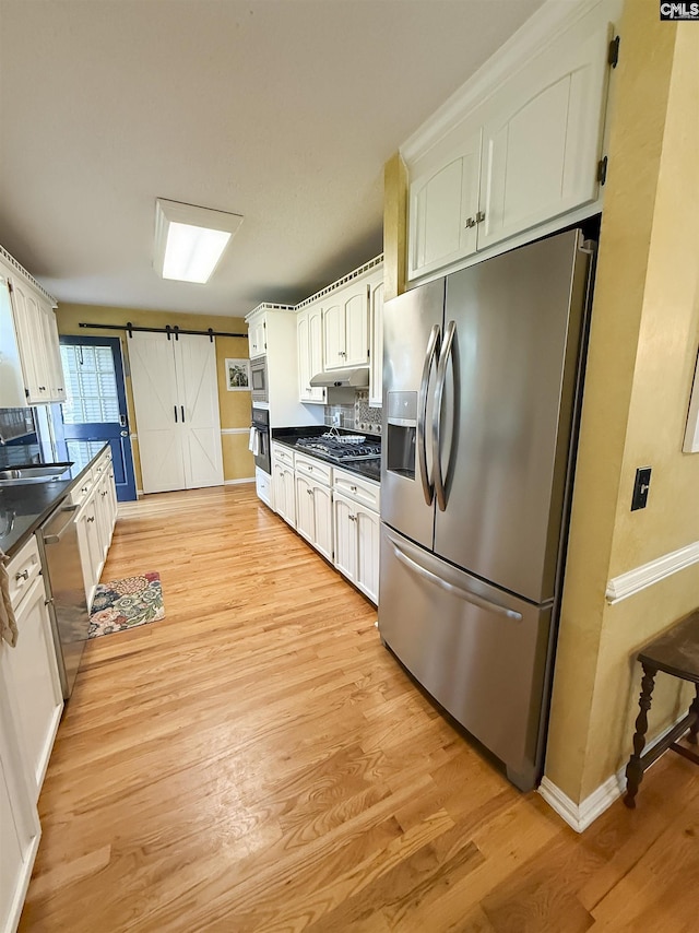 213 River Xing, Lexington, SC 29072 - kitchen with stainless steel appliances, light wood finished floors, under cabinet range hood, a barn door, and dark countertops