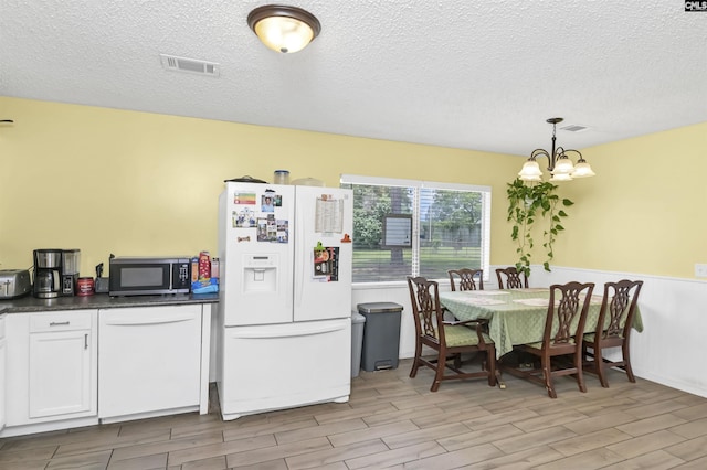 112 S Wrenwood Dr, Lexington, SC 29073 - kitchen with white appliances, a chandelier, dark countertops, a wainscoted wall, and light wood-style flooring