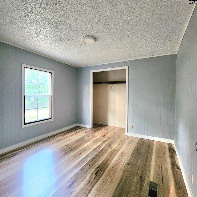 137 Breezy Bay Cir, Gilbert, SC 29054 - unfurnished bedroom featuring wood finished floors, a closet, a textured ceiling, baseboards, and wood walls