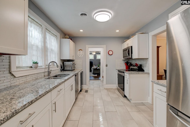 4524 Mosshill Rd, Columbia, SC 29206 - kitchen with appliances with stainless steel finishes, a sink, decorative backsplash, light tile patterned floors, and light stone countertops
