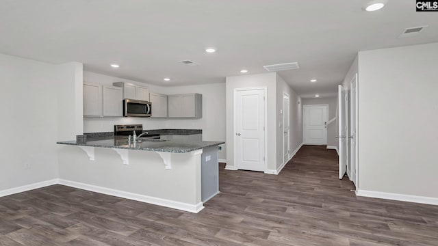 11A Beechnut St, Lugoff, SC 29078 - kitchen featuring appliances with stainless steel finishes, gray cabinets, a breakfast bar area, dark stone countertops, and a peninsula
