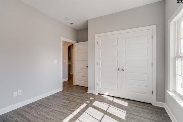 2752 Pawtucket Way, Chapin, SC 29036 - unfurnished bedroom featuring arched walkways, wood finished floors, a closet, and baseboards