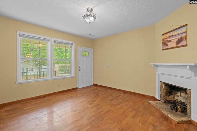 114 Quattlebaum Ave, Ridge Spring, SC 29129 - unfurnished living room with a fireplace with raised hearth, wood finished floors, baseboards, and a textured ceiling