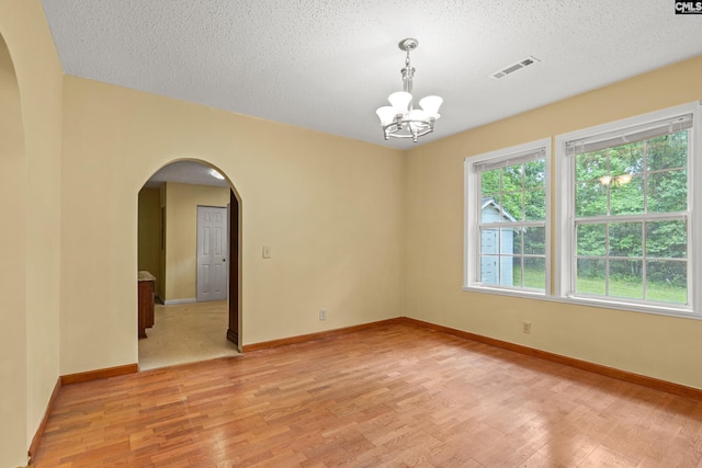 114 Quattlebaum Ave, Ridge Spring, SC 29129 - unfurnished room with arched walkways, a chandelier, light wood-style floors, a textured ceiling, and baseboards