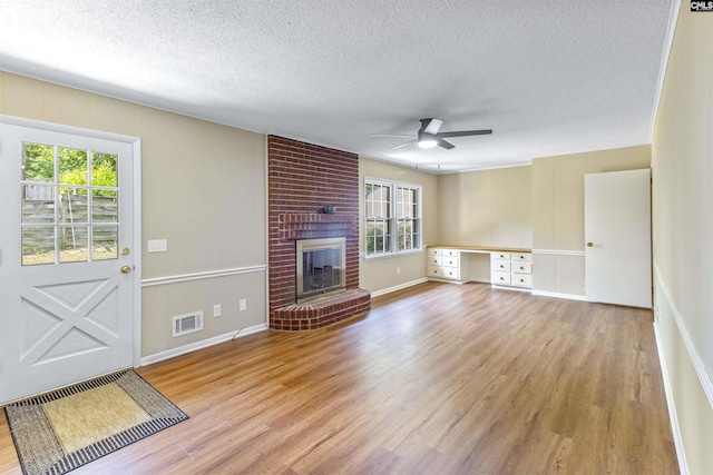 1109 F Ave, Cayce, SC 29033 - unfurnished living room with light wood-style flooring, a textured ceiling, a ceiling fan, plenty of natural light, and a brick fireplace