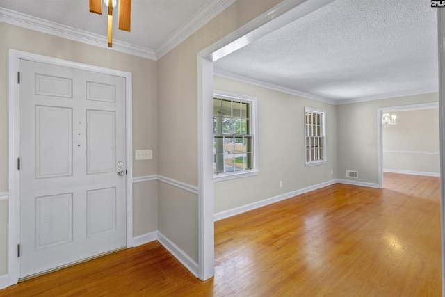 1109 F Ave, Cayce, SC 29033 - foyer entrance featuring light wood-style flooring, a chandelier, baseboards, a textured ceiling, and crown molding